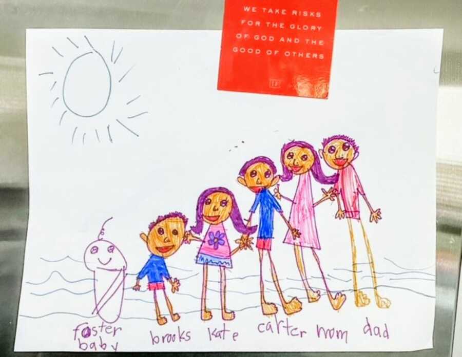 Young child draws a family picture, including his little foster brother