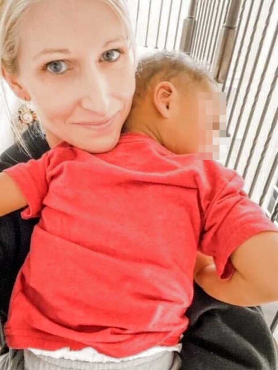 Foster mom takes a selfie of her foster son cuddling with her and sleeping on her shoulder in a red shirt