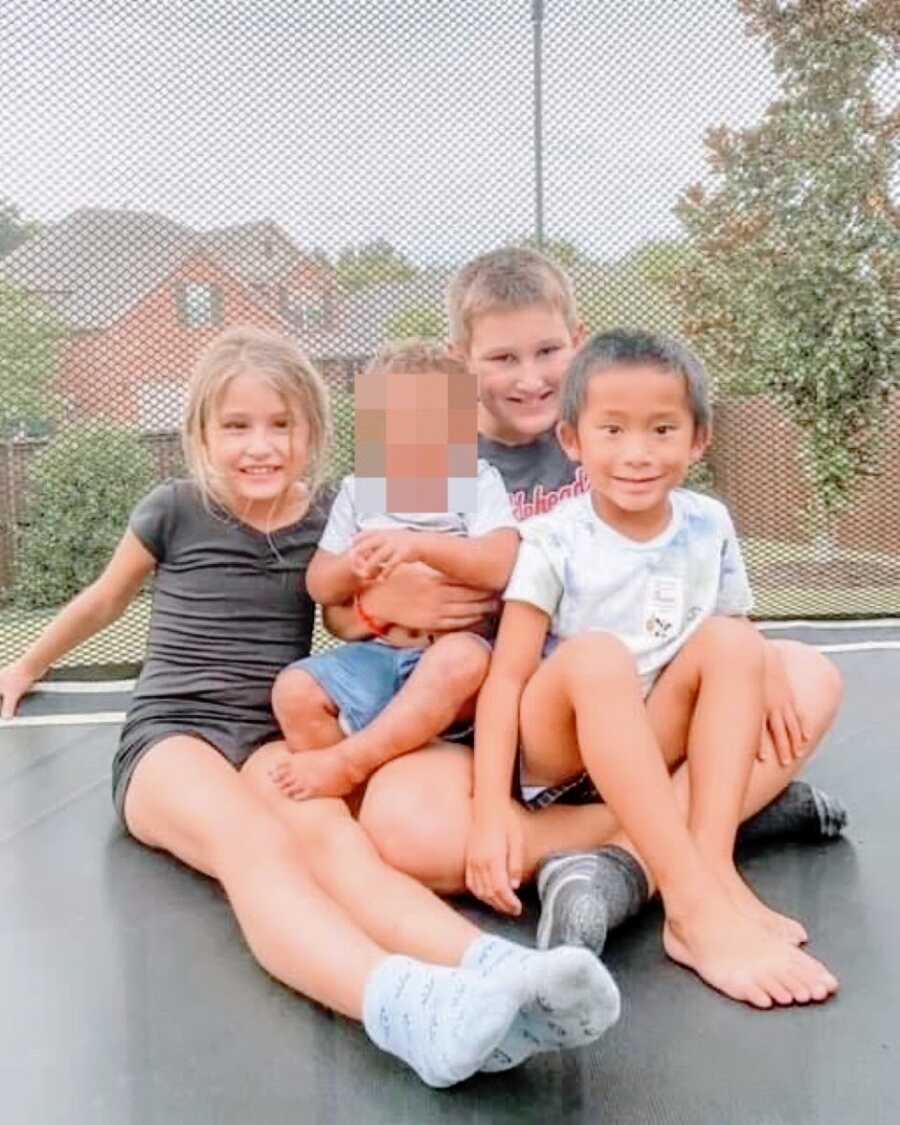 Mom takes a photo of her four kids, one in foster care and one adopted, spending time together on a trampoline
