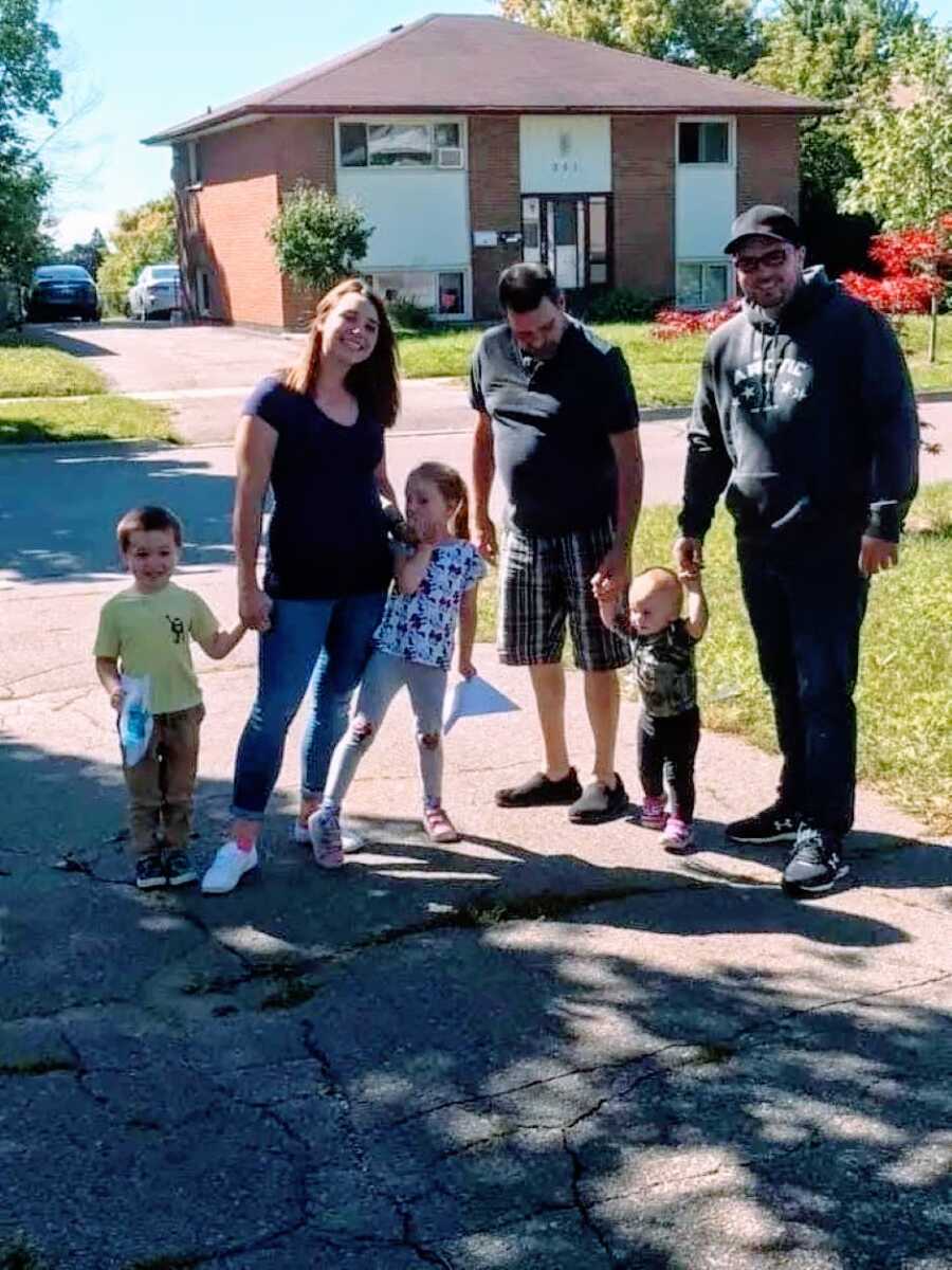 Family of five take a photo with their kids' grandfather in a driveway