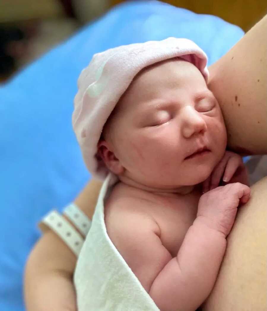 Mom holds her newborn daughter while she sleeps in her arms in the hospital