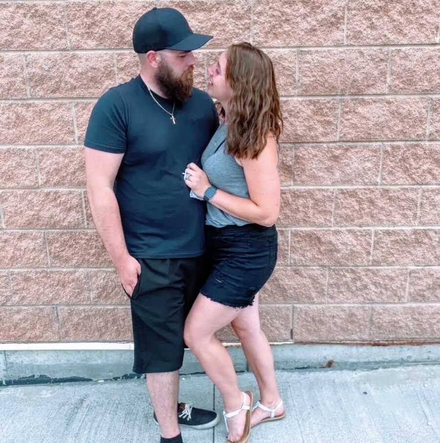 Couple look lovingly at each other while taking photos together, both in black and gray outfits