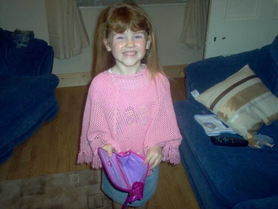 little girl smiling and holding a bag