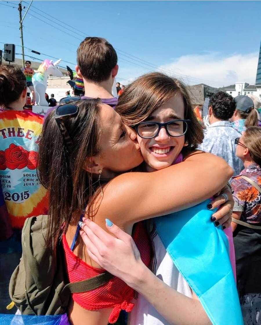 Mom kisses her transgender daughter on the cheek while they celebrate the LGBTQ+ community at a pride parade