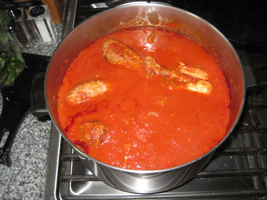 red sauce cooking with sausage in it