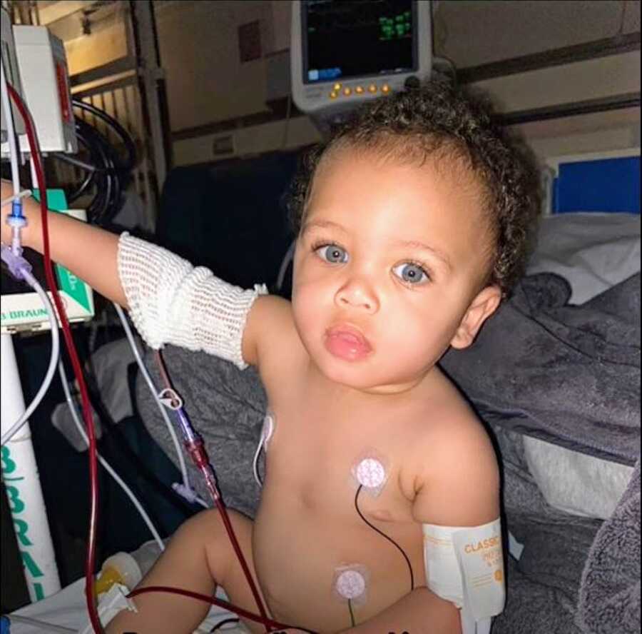 Young boy with rare genetic disorder sits in a hospital bed while attached to monitors and wires