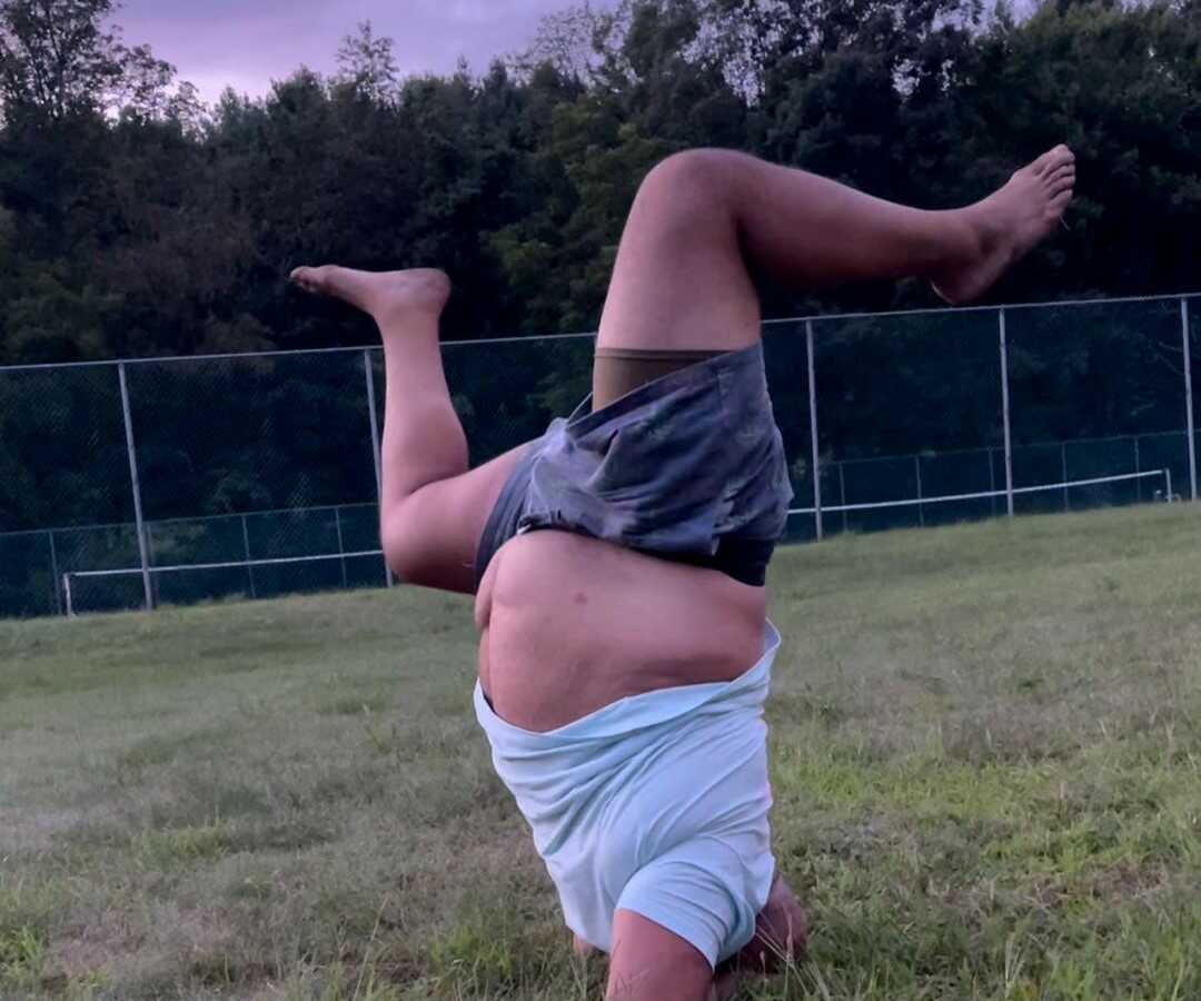 man standing on his head in the grass