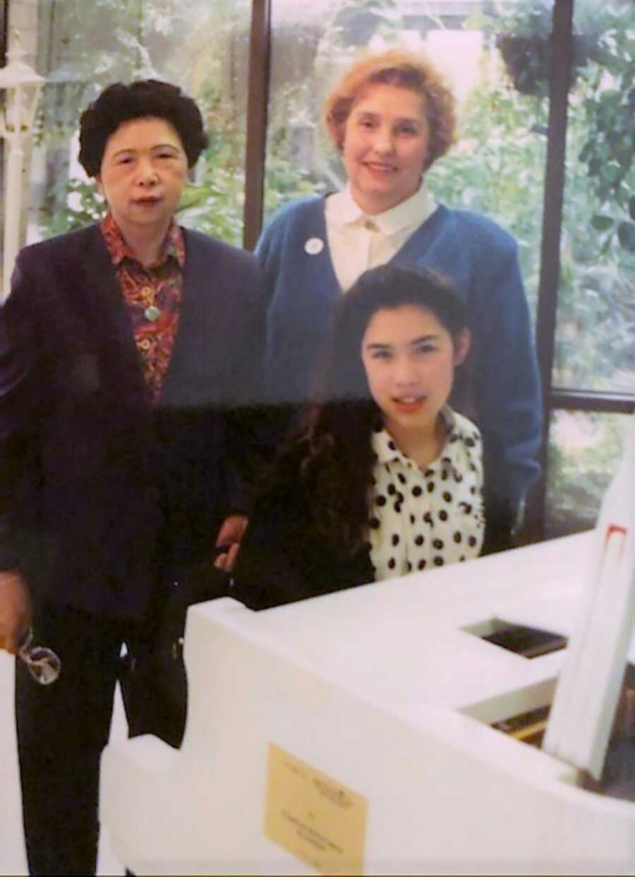Asian American teen girl playing the piano next to Asian and American family members