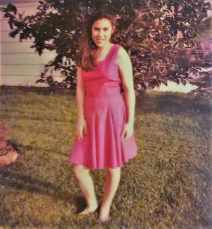 Teenage Asian American girl standing in the yard wearing a pink dress