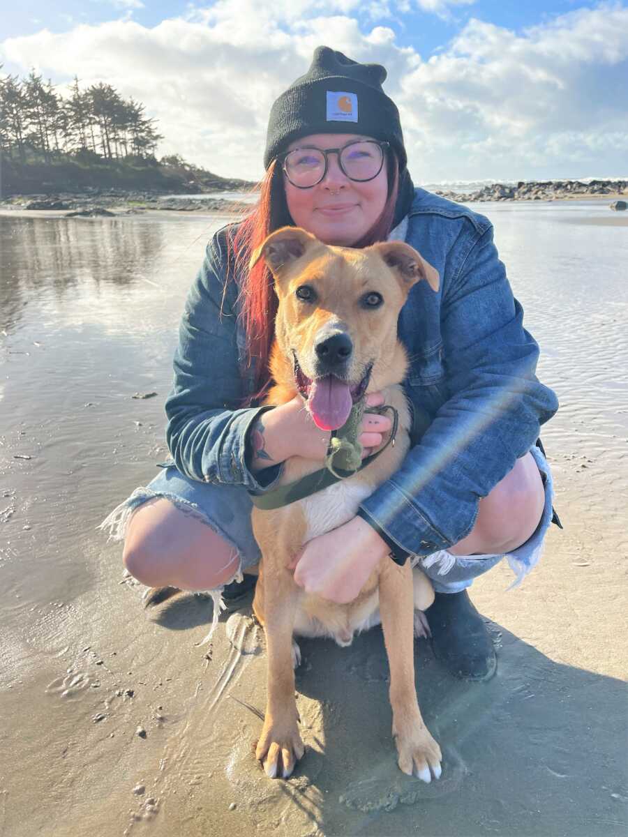 a girl and her rescued dog sitting at the beach 
