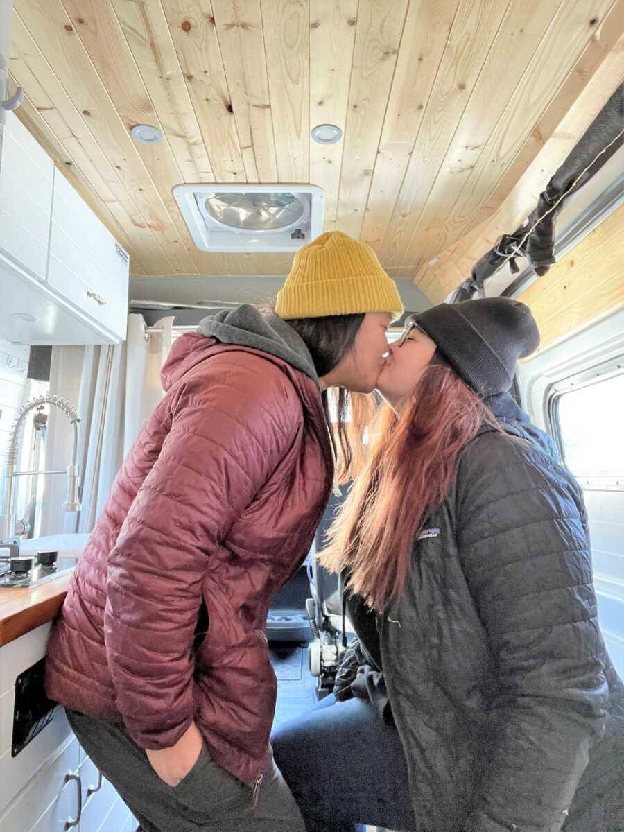 LGBT couple kissing inside of a camper van