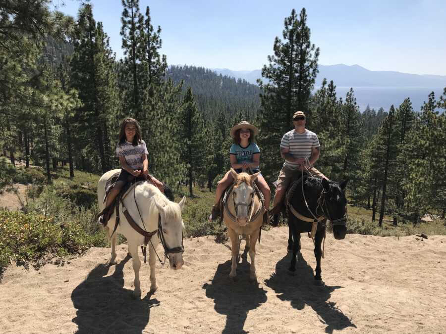 dad taking picture with his kids on horse