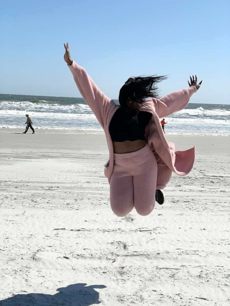 woman jumping in the air at the beach