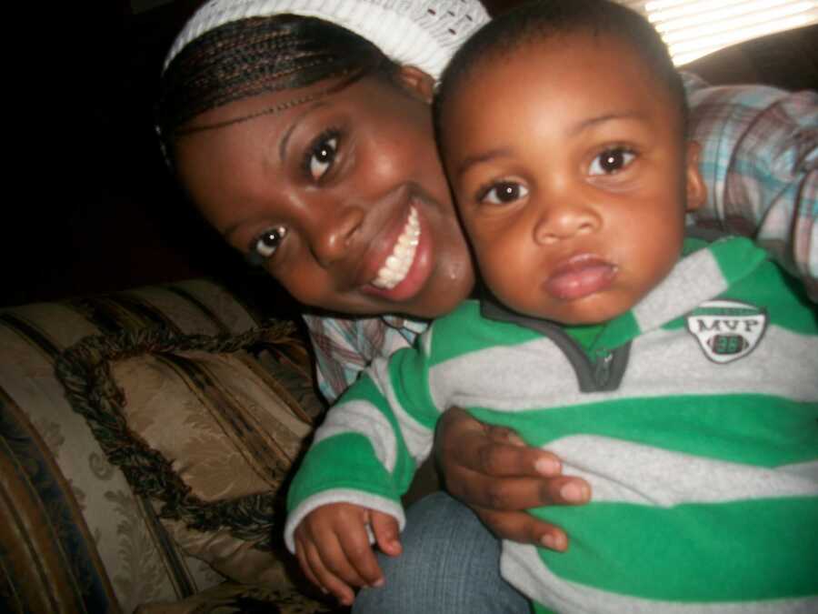 A young mom and her baby son who is wearing a green and grey striped shirt