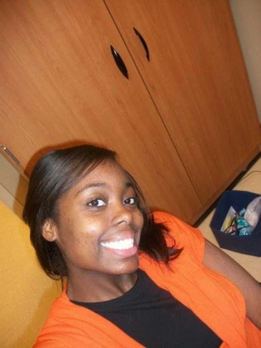 A young mom wearing an orange sweater and a black shirt