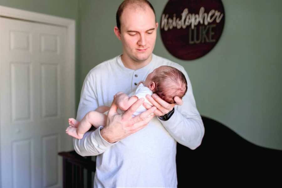 New father holds his newborn son for newborn photoshoot in his nursery