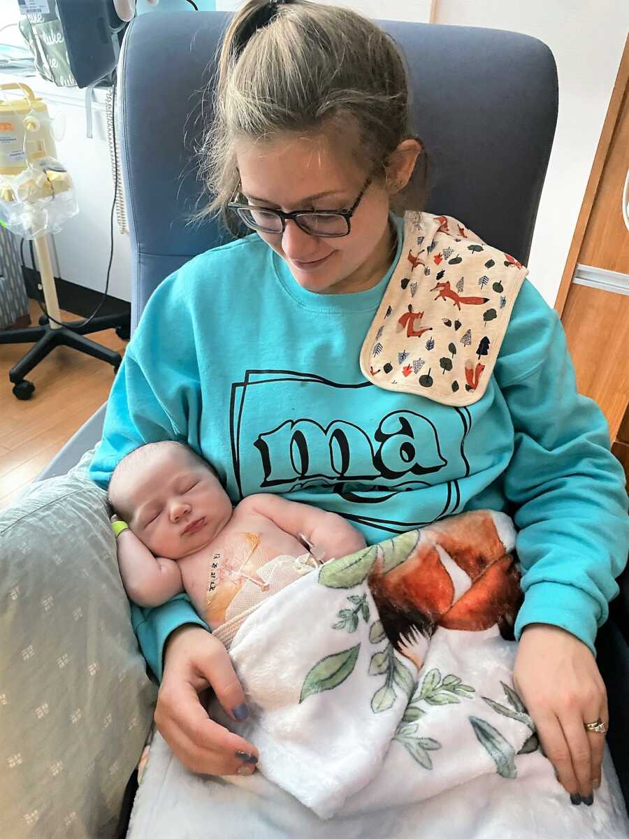 Mom holding newborn baby on her lap while he receives treatment for his cancer at the NICU