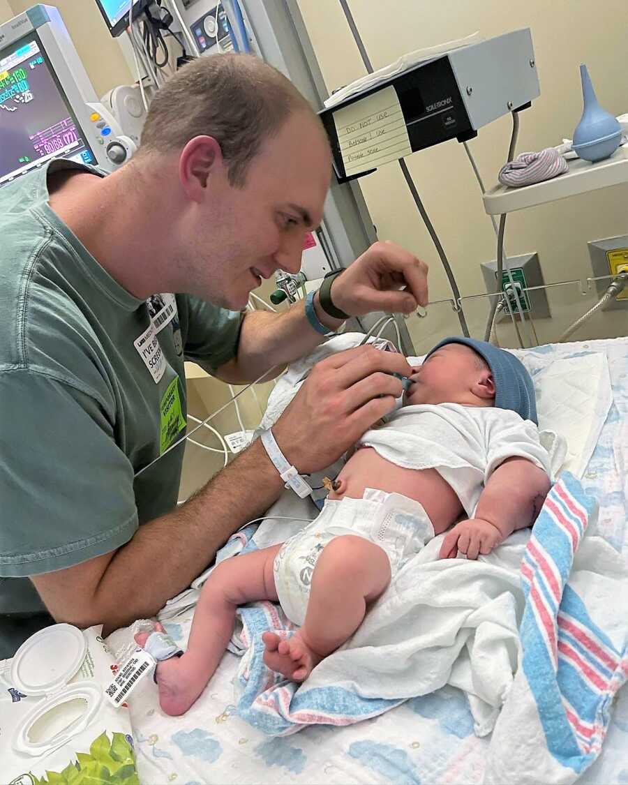 Dad putting a pacifier on his newborn baby's mouth while he lays on a bed at the NICU because of his Cancer diagnosis