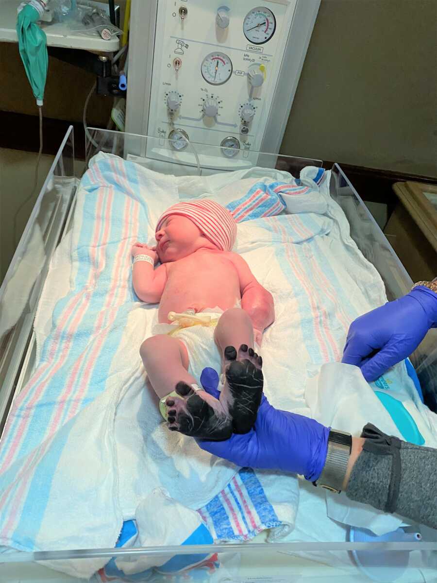 Newborn baby with ink on his feet while they take his footprint at the Hospital