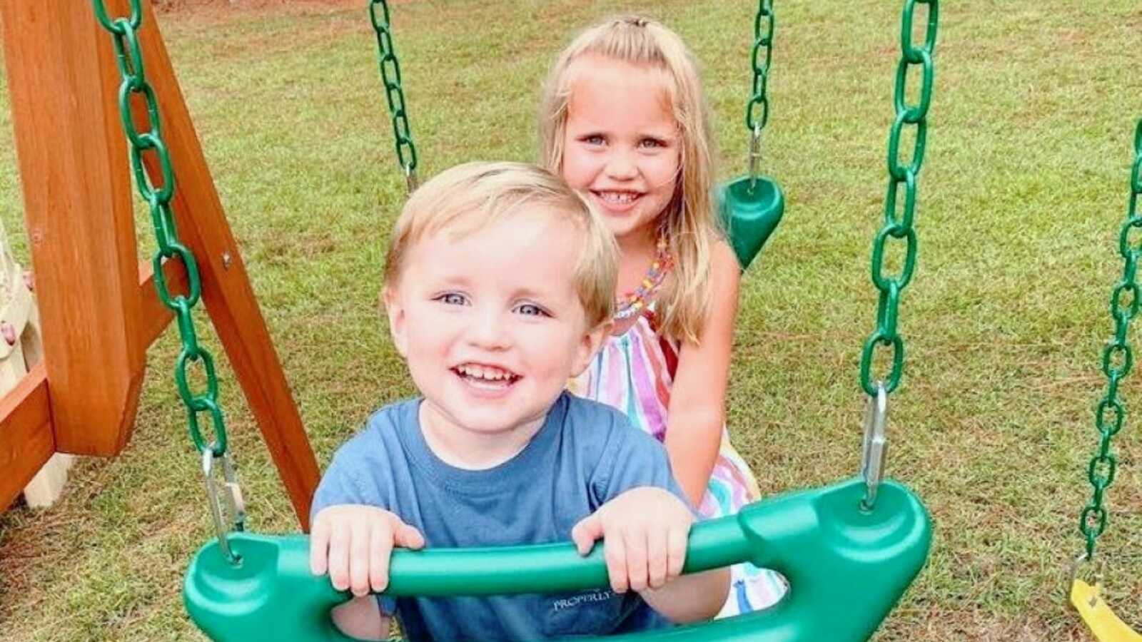 Brother and sister enjoy outside time on a swing together