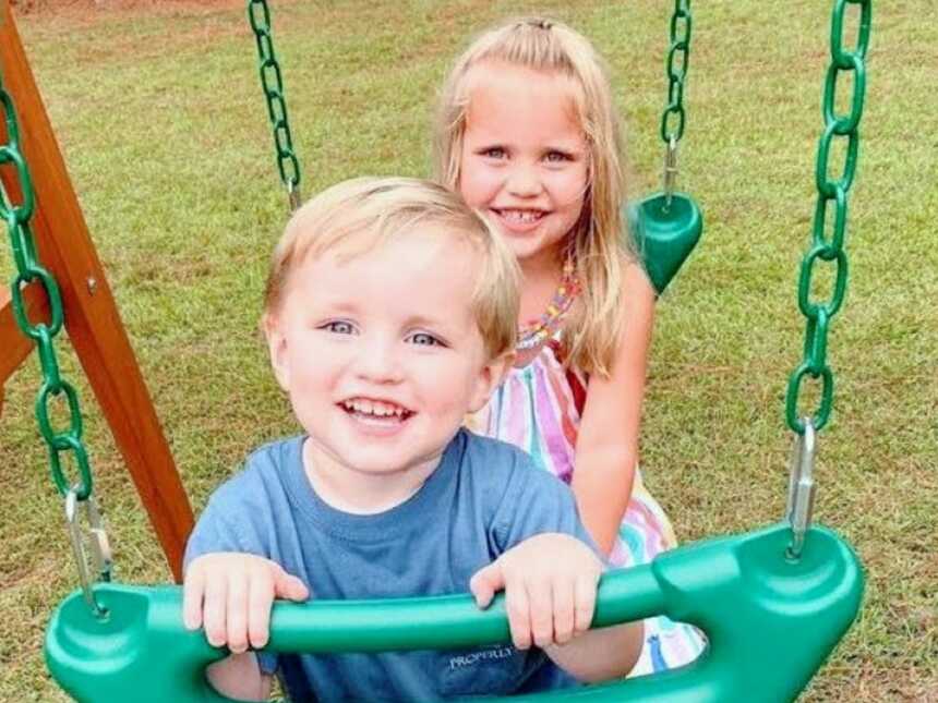 Brother and sister enjoy outside time on a swing together