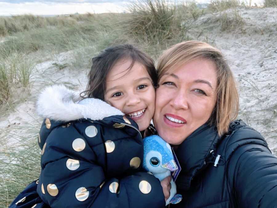 Mom takes a selfie with her daughter while they spend time on the beach