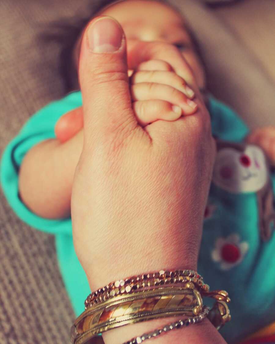 Newborn daughter holds onto her mom's hand in touching photo
