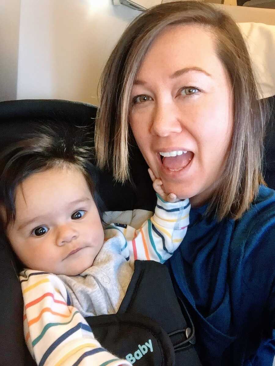 Woman takes a selfie with her toddler daughter while they sit and play on the couch together