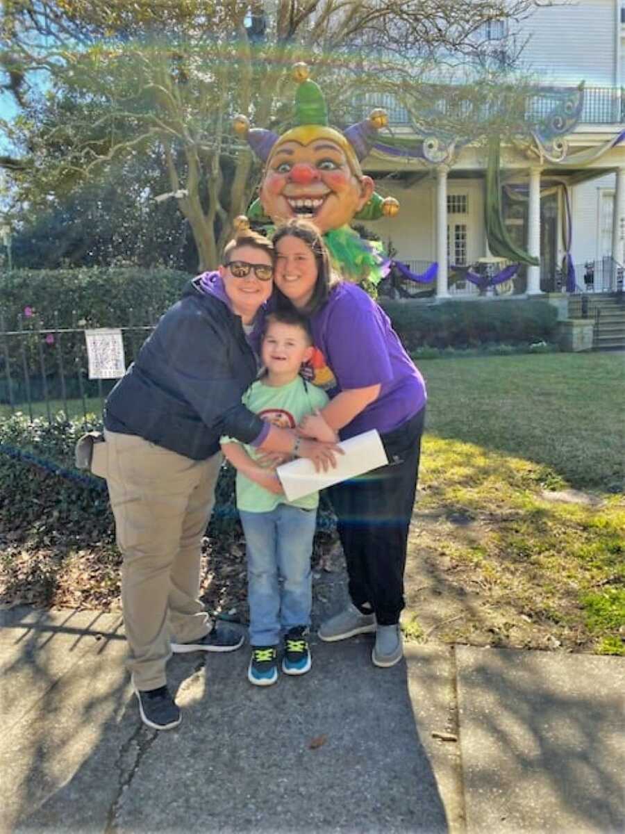 lesbian moms hugging their autistic son with a clown statue in the back