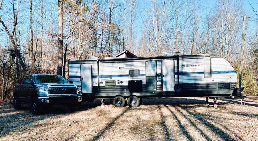 Photo of a large RV next to a blue Toyota Tundra a family of three is living and traveling in