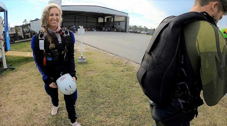 Young woman getting equipment ready to start skydiving lesson to get skydiving license 