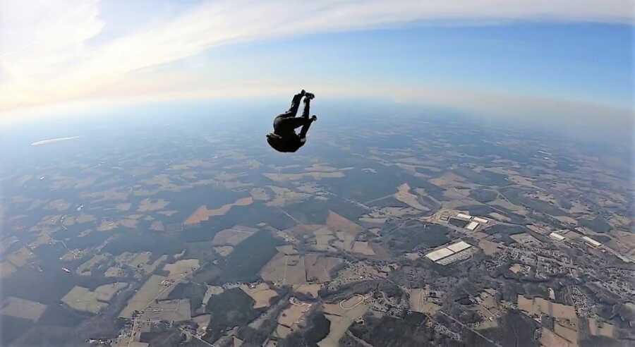 Young woman doing a flip in the air while skydiving 