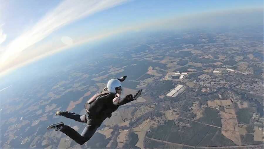 Young woman skydiving solo with her arms and legs extended in the air 