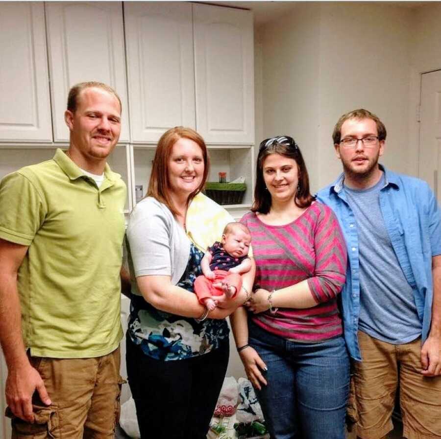 Birth parents and adoptive parents take a group photo together with their shared daughter