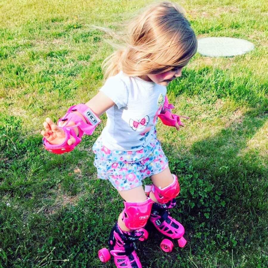 Little girl jumps around in pink skates and elbow and knee pads