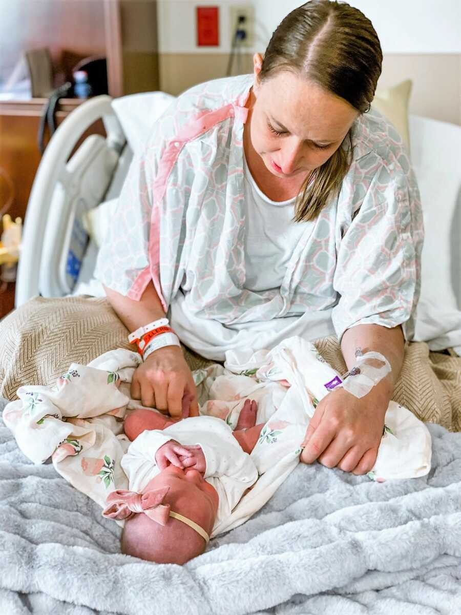 Gestational carrier at the hospital holding newborn baby girl on her lap 