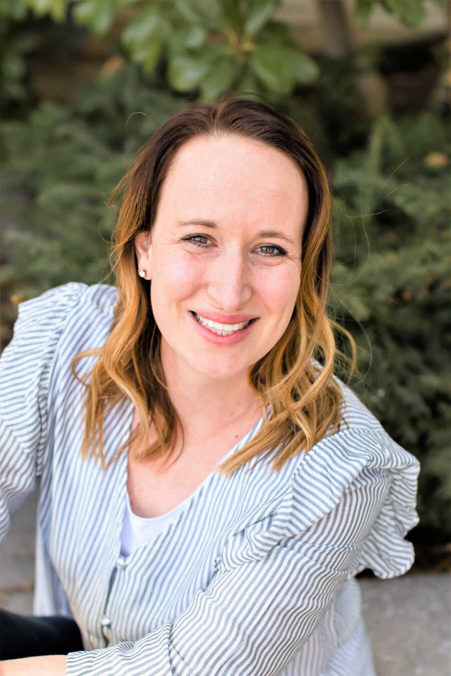 Portrait of a woman smiling with tree in the background 