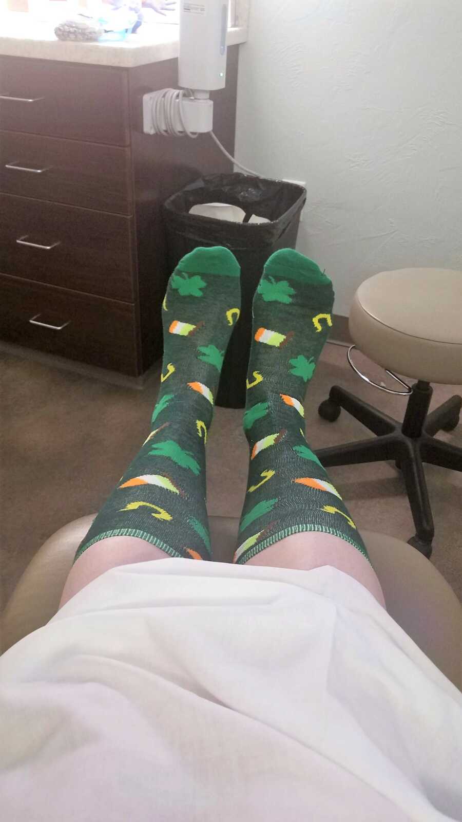 picture of a woman's legs and feet wearing Irish themed socks at a doctors appointment 