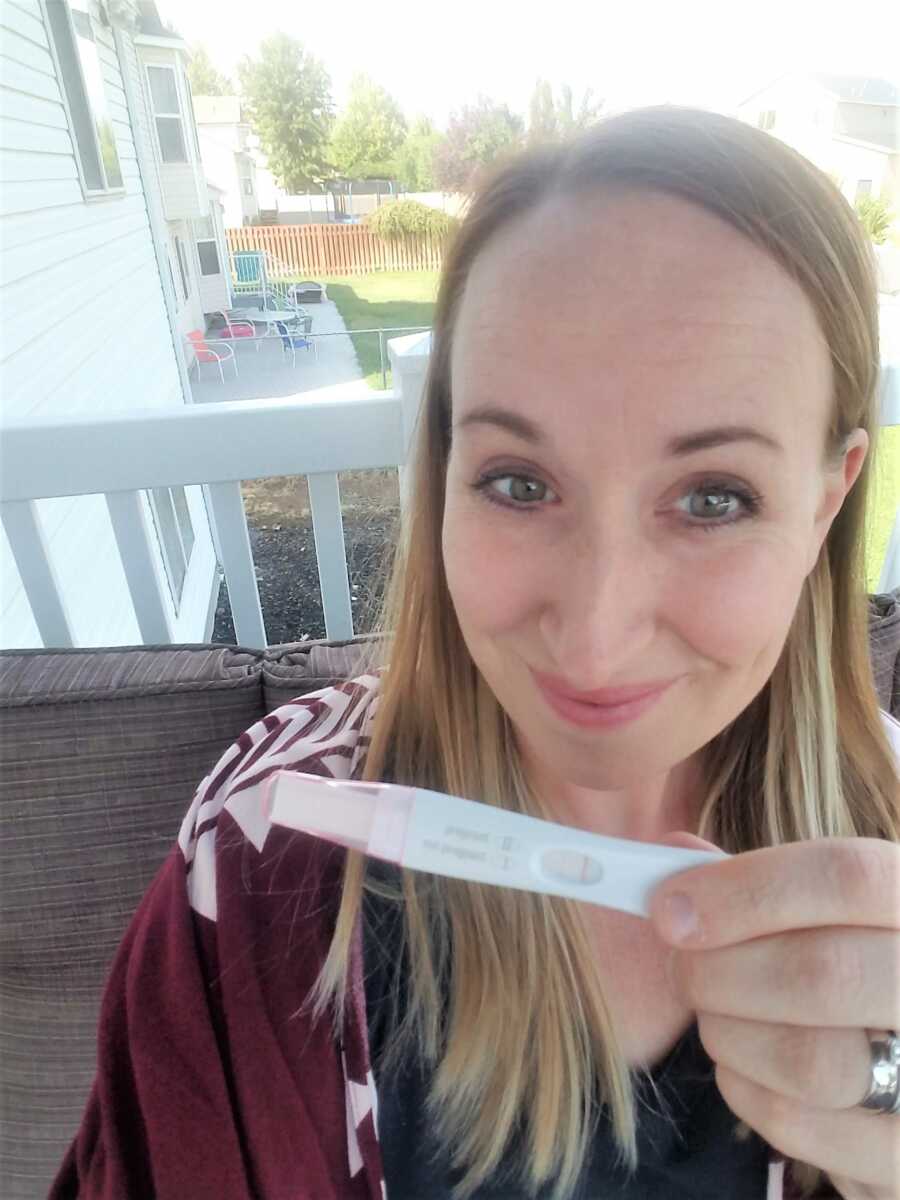 Selfie of woman holding a positive pregnancy test 