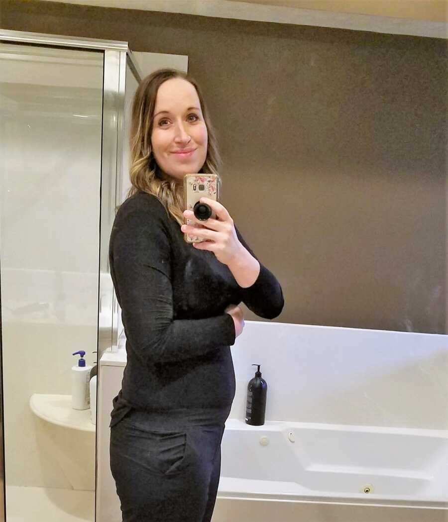 Pregnant woman taking a mirror selfie in the bathroom