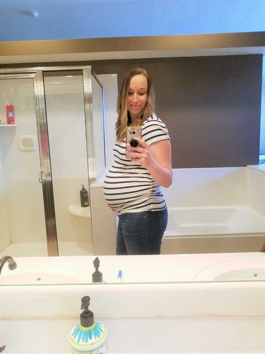 Pregnant woman taking a mirror selfie in the bathroom