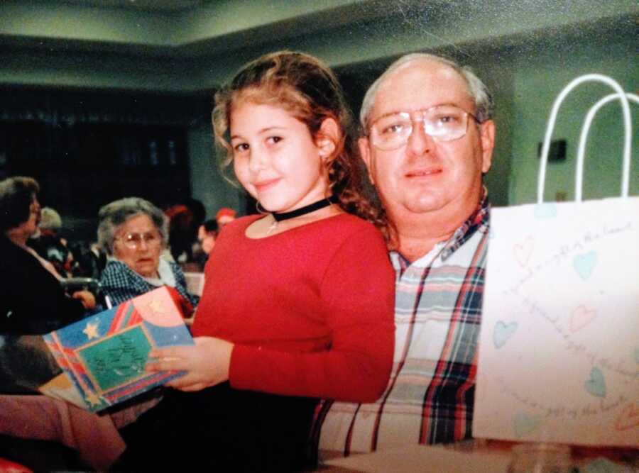 Young girl stands next to her adoptive father for a photo in church