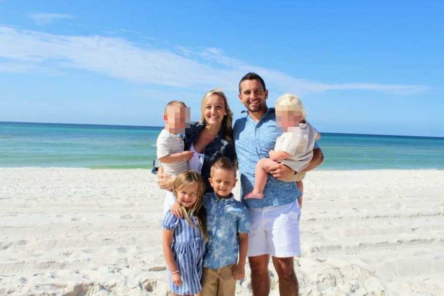 Family of six take a photo on the beach with their biological twin children and their two foster sons