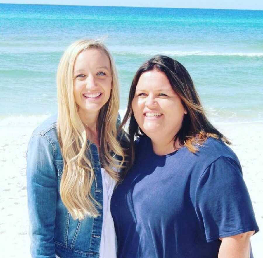 Foster moms smile for a photo together while both wearing blue at the beach