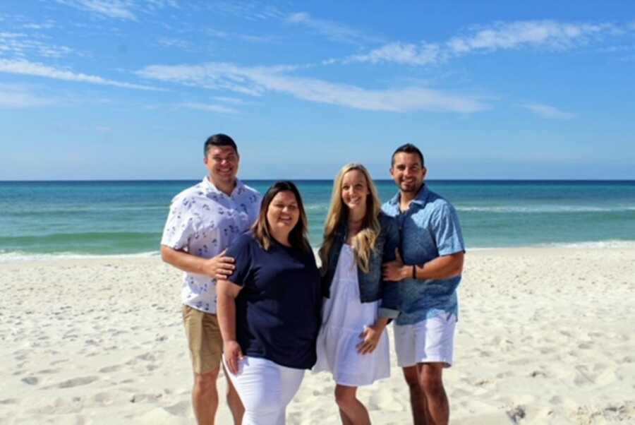 Two foster couples pose for a photo on the beach together in color-coordinated outfits