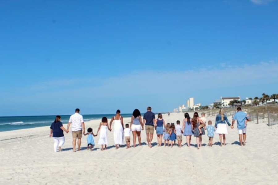 Two foster families take huge group photo as they all walk down the beach hand-in-hand