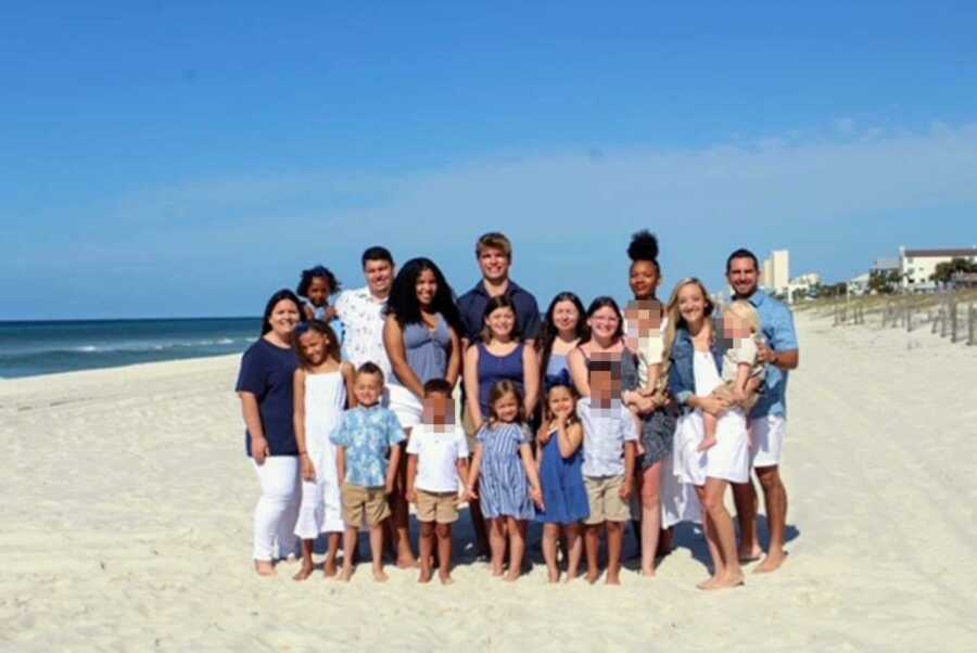 Two foster families take group photo on the beach in color-coordinated outfits