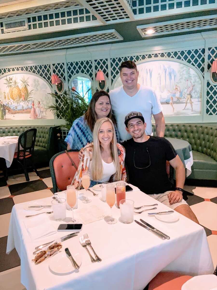 Two foster couples take a photo together while out for dinner without their kids
