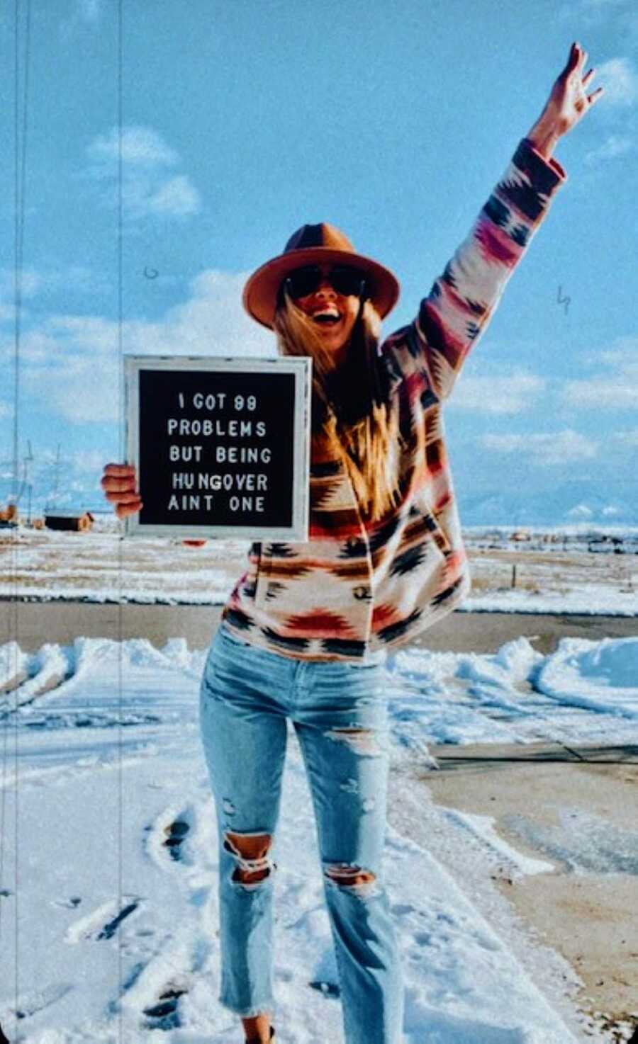 Woman celebrates her sobriety journey with a sign that reads "I got 99 problems but being hungover ain't one"