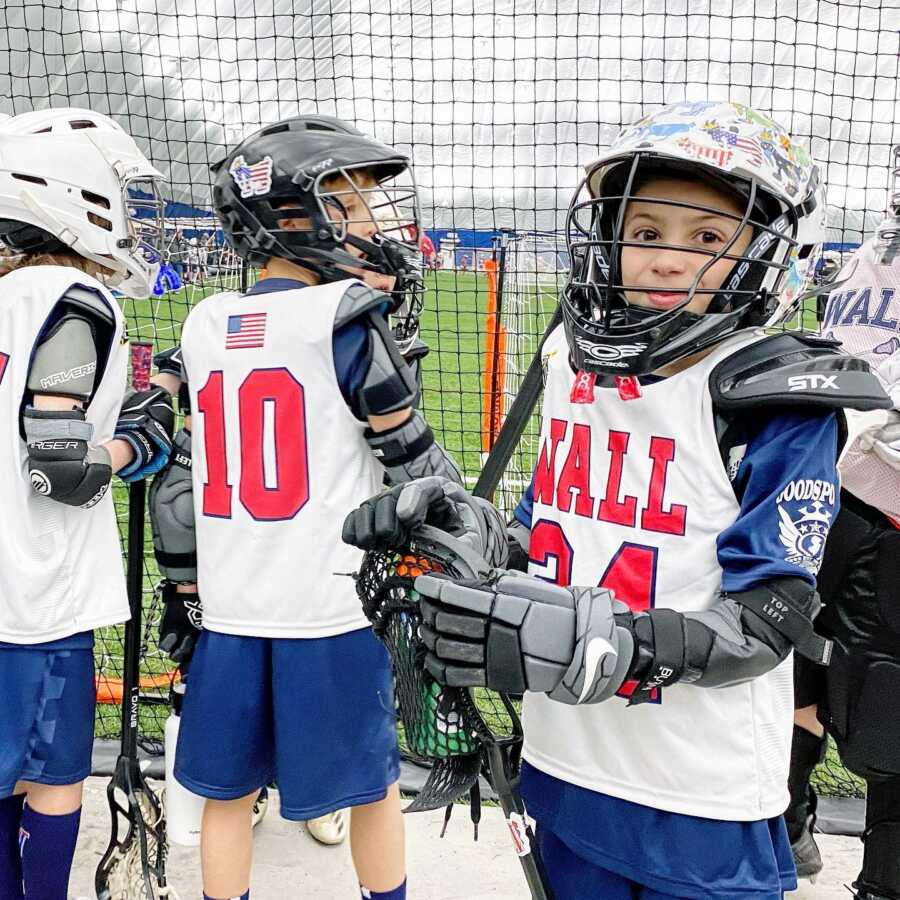 Young boy smiles for a photo while in his lacrosse uniform before a tournament